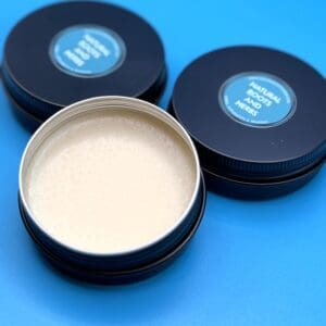 Three round tins of cream on a blue background.