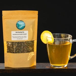 A bag of tea and a glass cup with lemon.